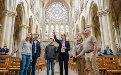 Tour group inside Notre-Dame Cathedral, Paris, admiring stained glass windows.