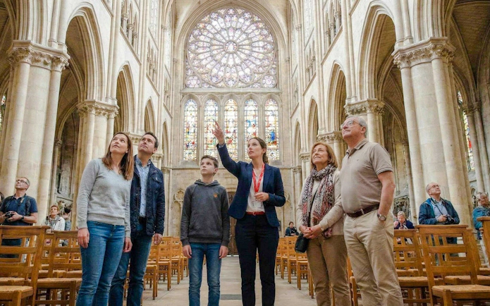 Tour group inside Notre-Dame Cathedral, Paris, admiring stained glass windows.
