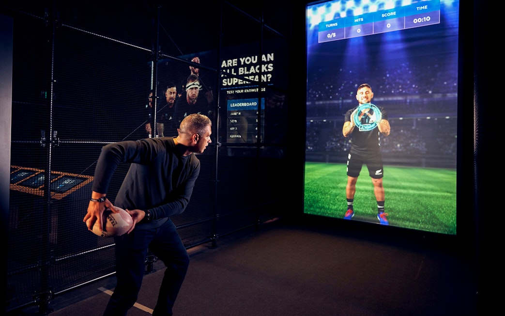 Man interacting with a digital rugby experience at All Blacks Experience, New Zealand.