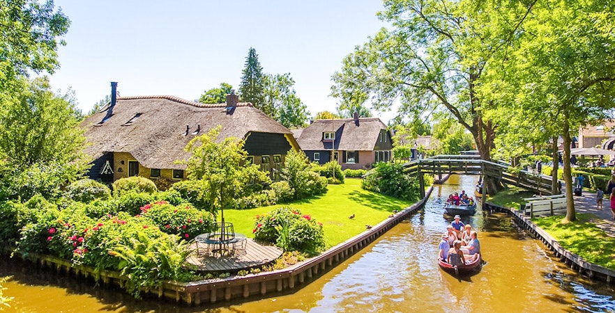 Giethoorn canal boat ride with traditional thatched-roof houses in the Netherlands.
