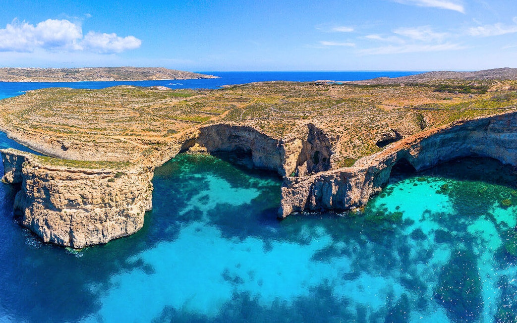 Aerial view of Crystal Lagoon's turquoise waters and rocky cliffs in Malta.
