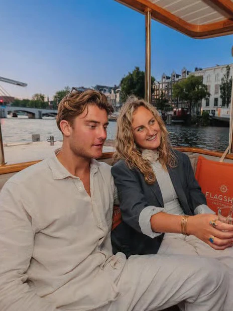 Couple enjoying wine on a luxury evening canal cruise in Amsterdam.