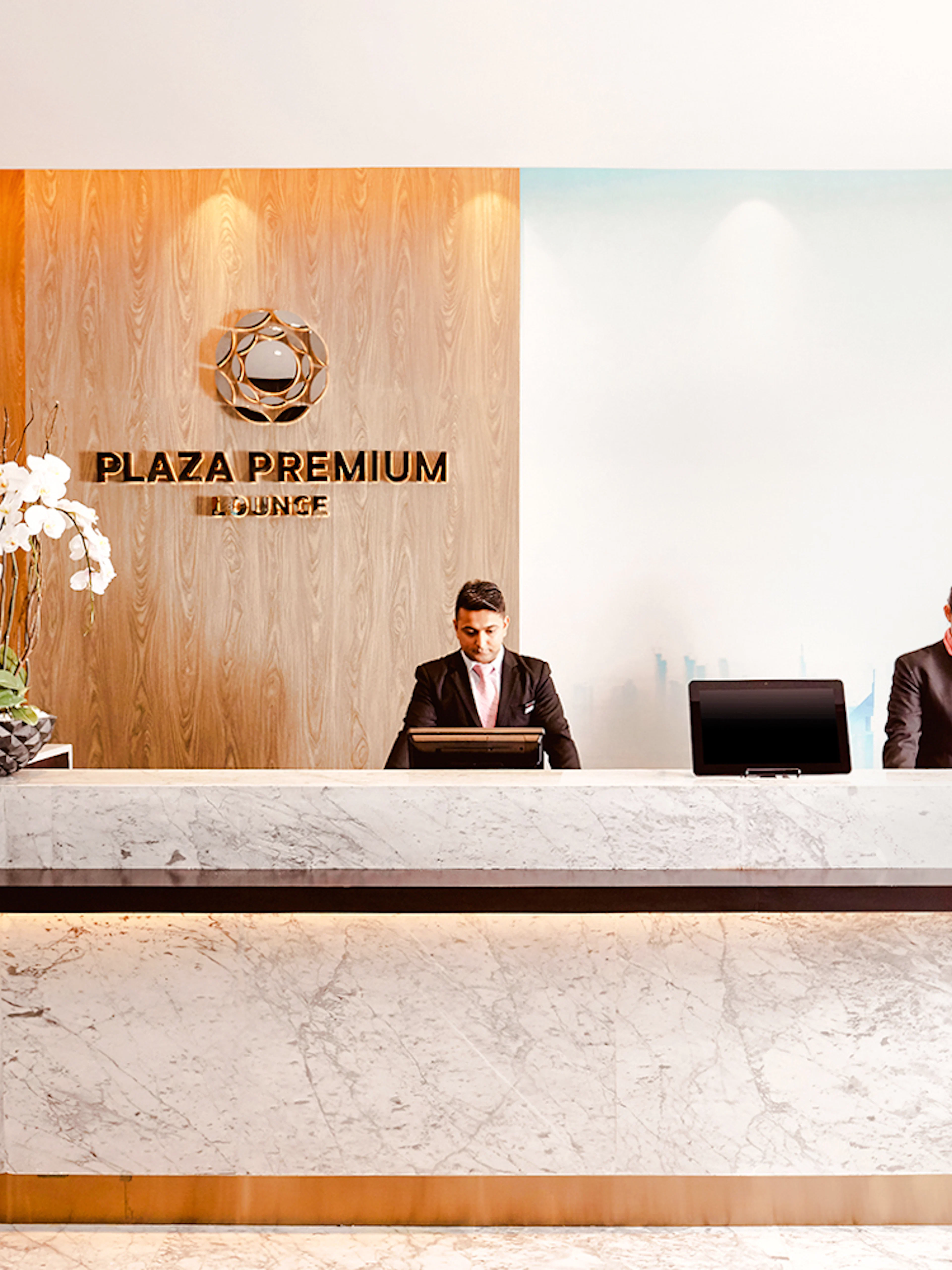 Plaza Premium Lounge reception at Dubai International Airport with staff at the counter.