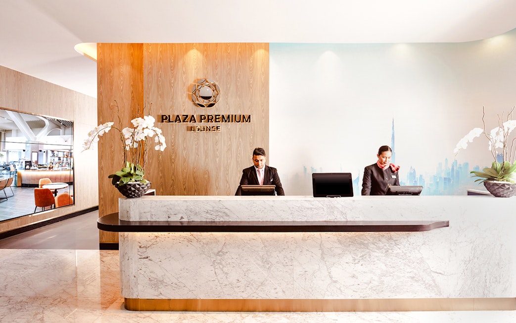 Plaza Premium Lounge reception at Dubai International Airport with staff at the counter.