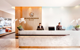 Plaza Premium Lounge reception at Dubai International Airport with staff at the counter.