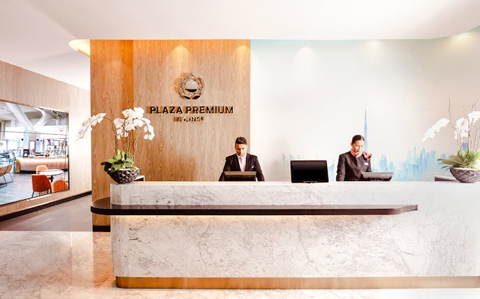 Plaza Premium Lounge reception at Dubai International Airport with staff at the counter.