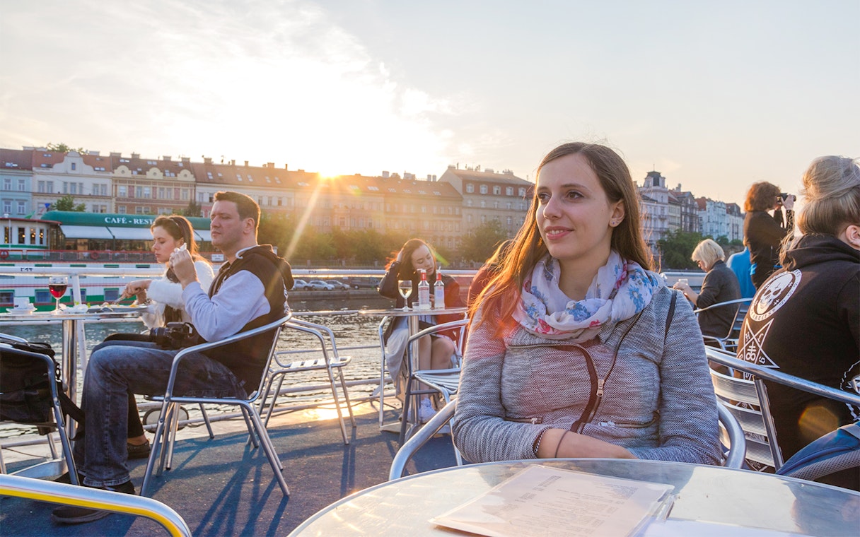 Woman enjoying a sunset cruise on the Vltava River in Prague.