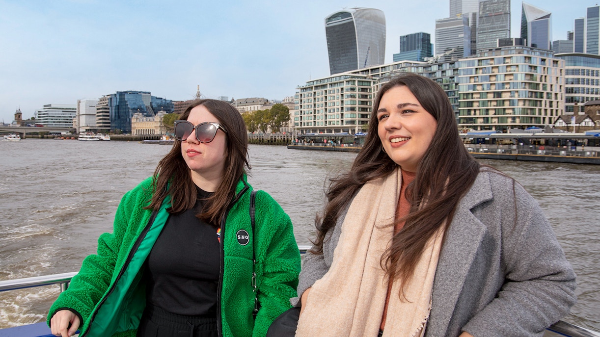 Women enjoying a Thames River afternoon cruise with London skyline in the background.