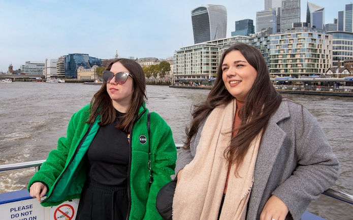 Women enjoying a Thames River afternoon cruise with London skyline in the background.