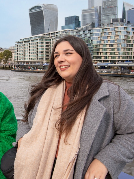 Women enjoying a Thames River afternoon cruise with London skyline in the background.