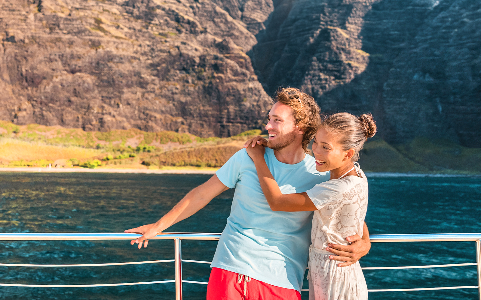 Couple enjoying a whale watching cruise with scenic cliffs in Oahu, Hawaii.