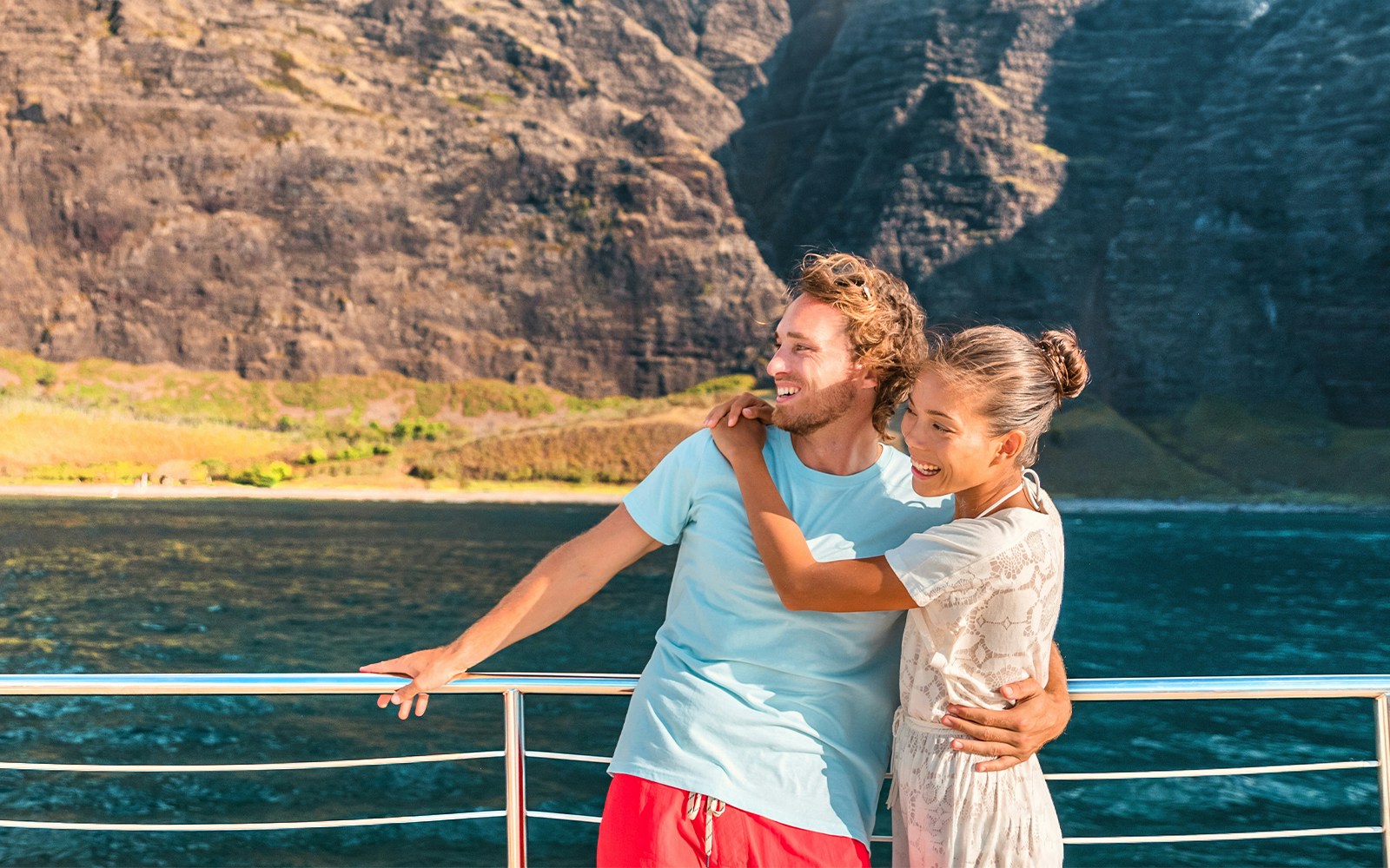 Couple enjoying a whale watching cruise with scenic cliffs in Oahu, Hawaii.
