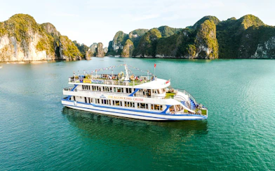 Delux Dragon King cruise ship sailing in Halong Bay, Vietnam, with limestone karsts in the background.