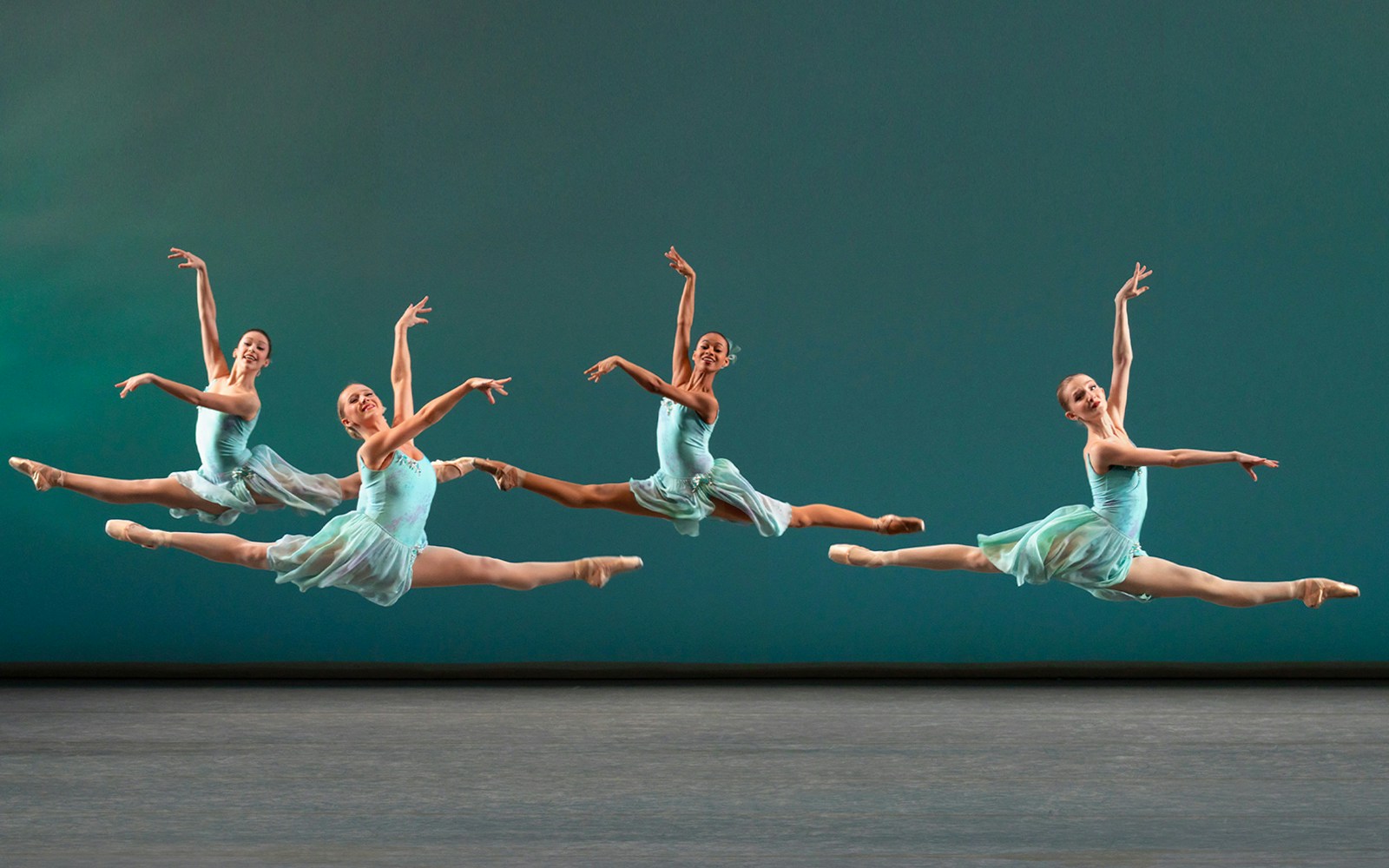 Ballet dancers performing a grand jeté at New York City Ballet.