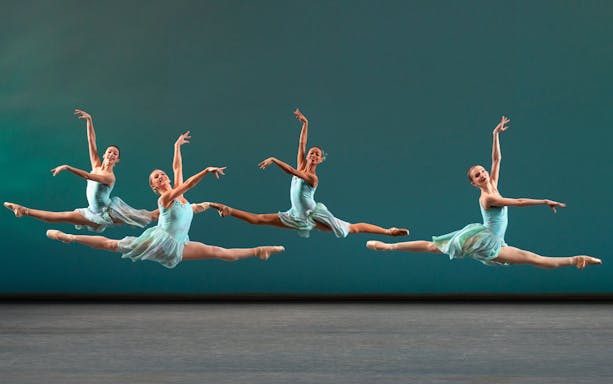 Ballet dancers performing a grand jeté at New York City Ballet.