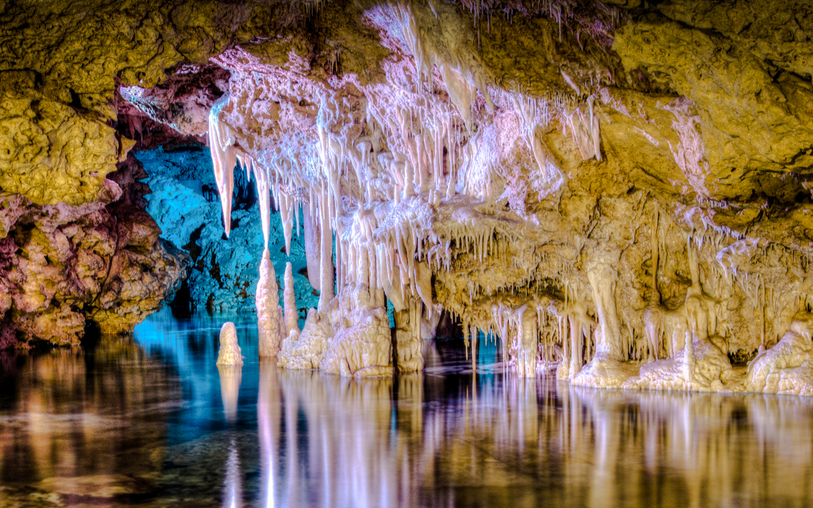 Stalactites and stalagmites inside Drach Caves, Mallorca, reflecting in underground lake.
