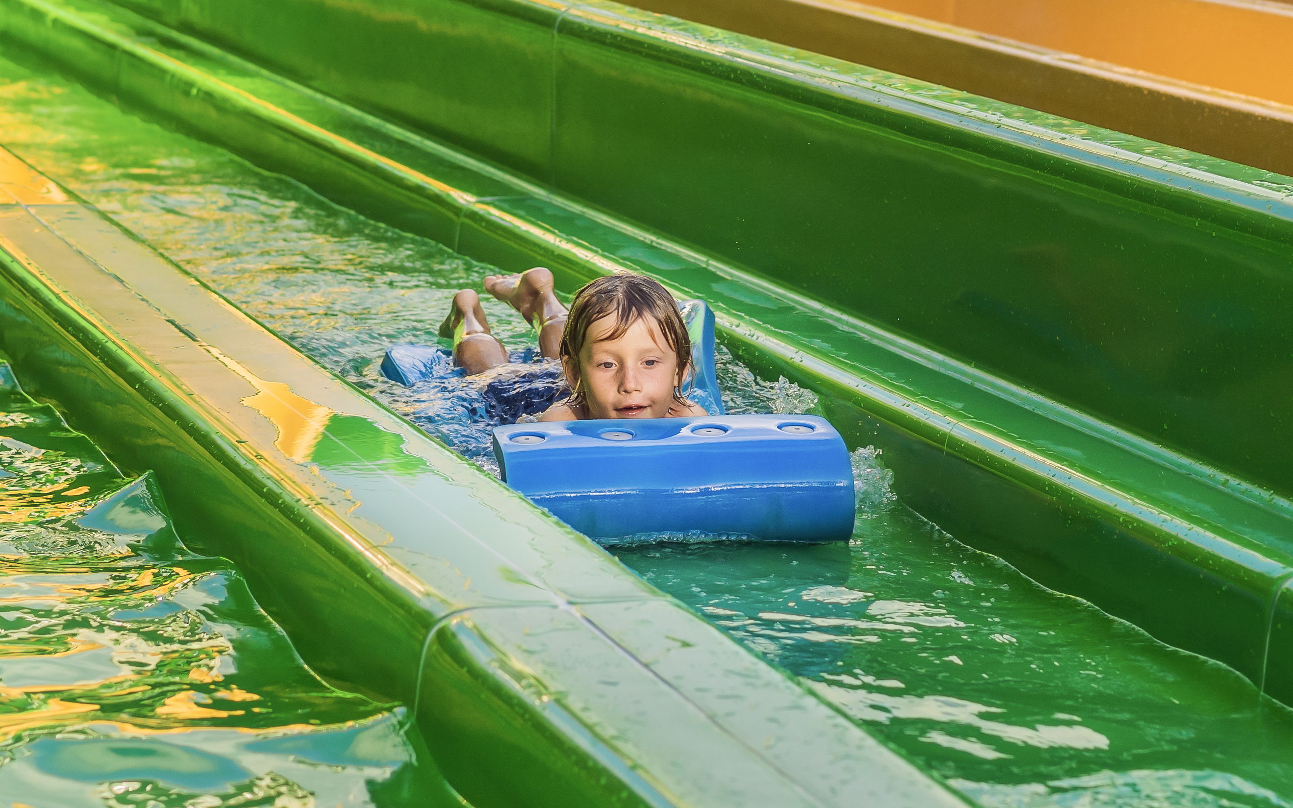 Boy sliding on a water slide at a tropical resort water park.