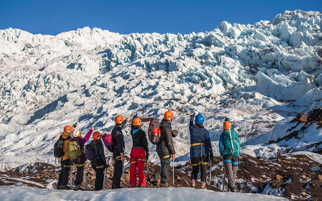 Guests hiking on Vatnajökull Glacier in Iceland, wearing helmets and gear.