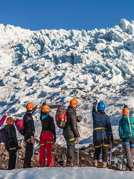 Guests hiking on Vatnajökull Glacier in Iceland, wearing helmets and gear.