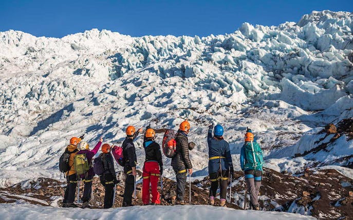 Guests hiking on Vatnajökull Glacier in Iceland, wearing helmets and gear.