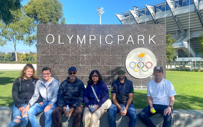 Group sitting at Melbourne Olympic Park sign during sports walking tour.