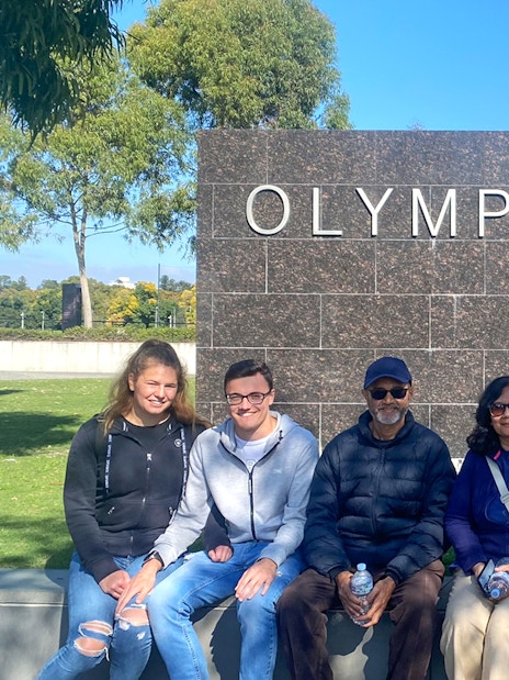 Group sitting at Melbourne Olympic Park sign during sports walking tour.