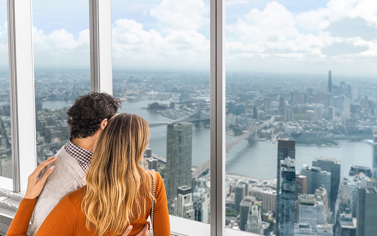 Couple enjoying panoramic views of New York City skyline from One World Observatory.