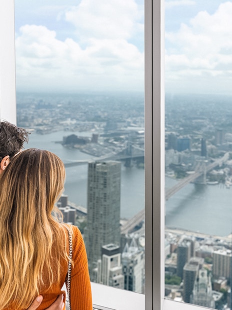 Couple enjoying panoramic views of New York City skyline from One World Observatory.