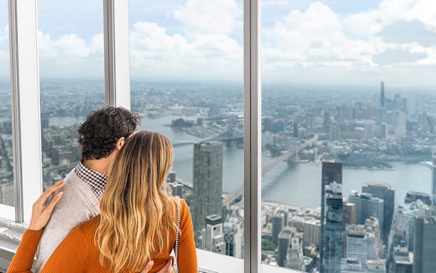 Couple enjoying panoramic views of New York City skyline from One World Observatory.