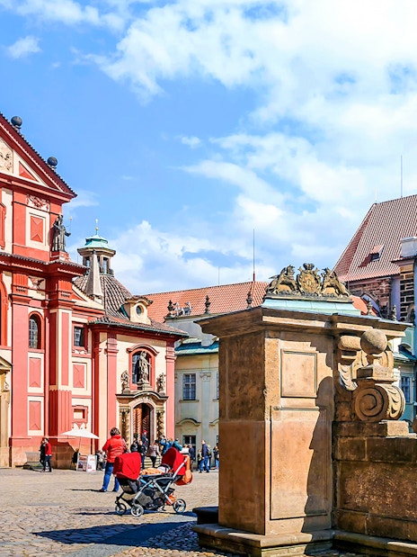 Prague Castle courtyard with St. George's Basilica, tourists exploring.