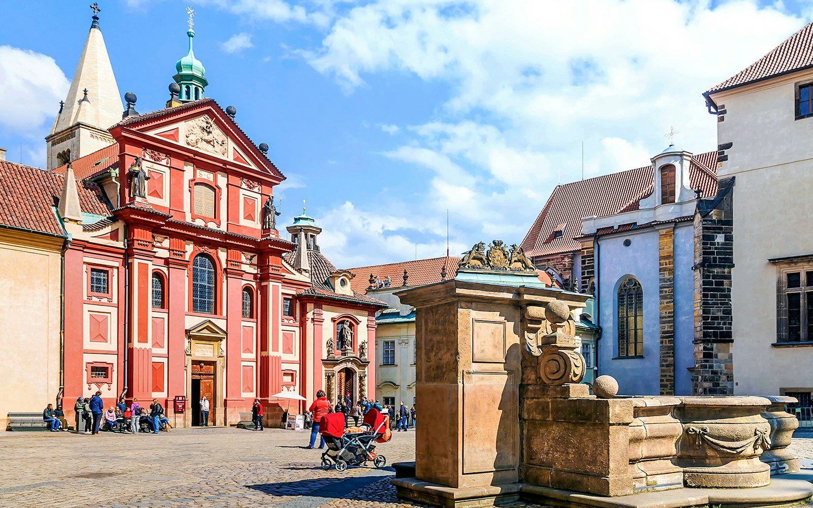 Prague Castle courtyard with St. George's Basilica, tourists exploring.