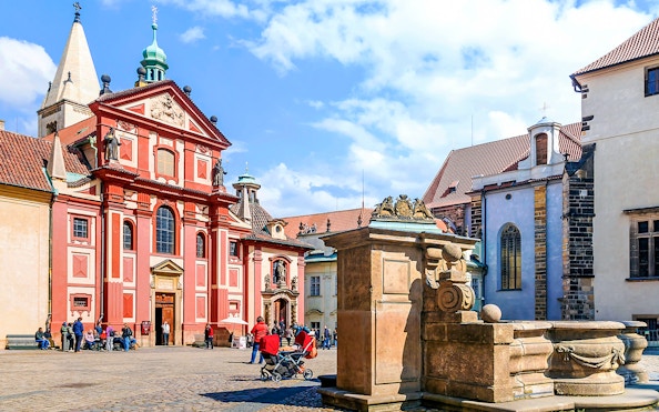 Prague Castle courtyard with St. George's Basilica, tourists exploring.