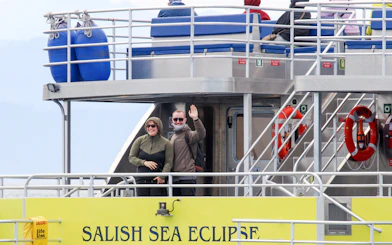 Guests waving on the Salish Sea Eclipse catamaran deck.