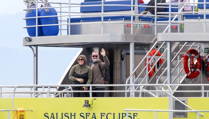 Guests waving on the Salish Sea Eclipse catamaran deck.