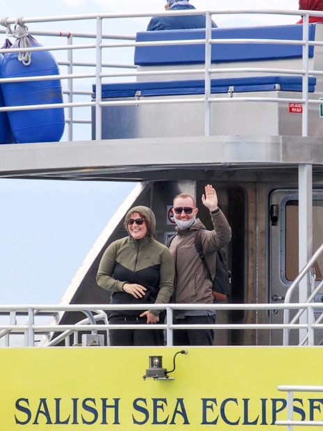 Guests waving on the Salish Sea Eclipse catamaran deck.
