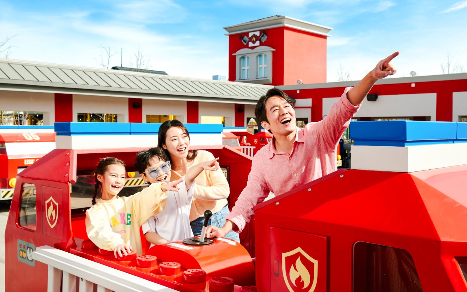 Family enjoying a ride at Legoland, pointing at attractions.