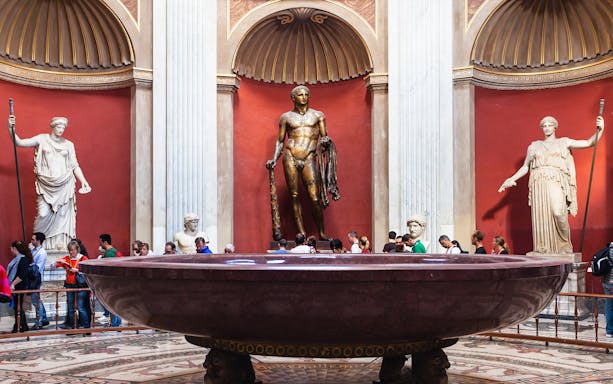 Vatican Museums visitors near ancient statues and large basin, Rome tour.