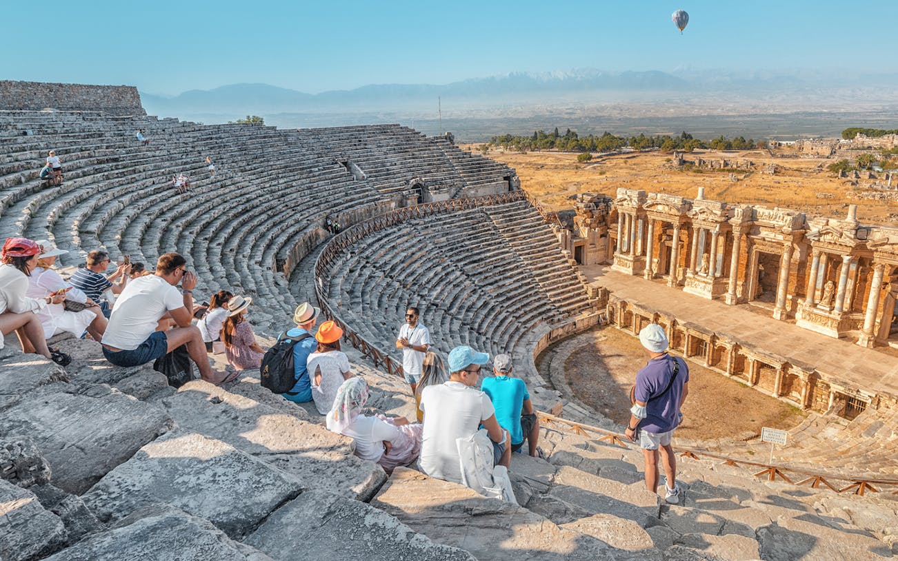 Ancient theater in Aspendos with tourists seated, part of Antalya guided tour.