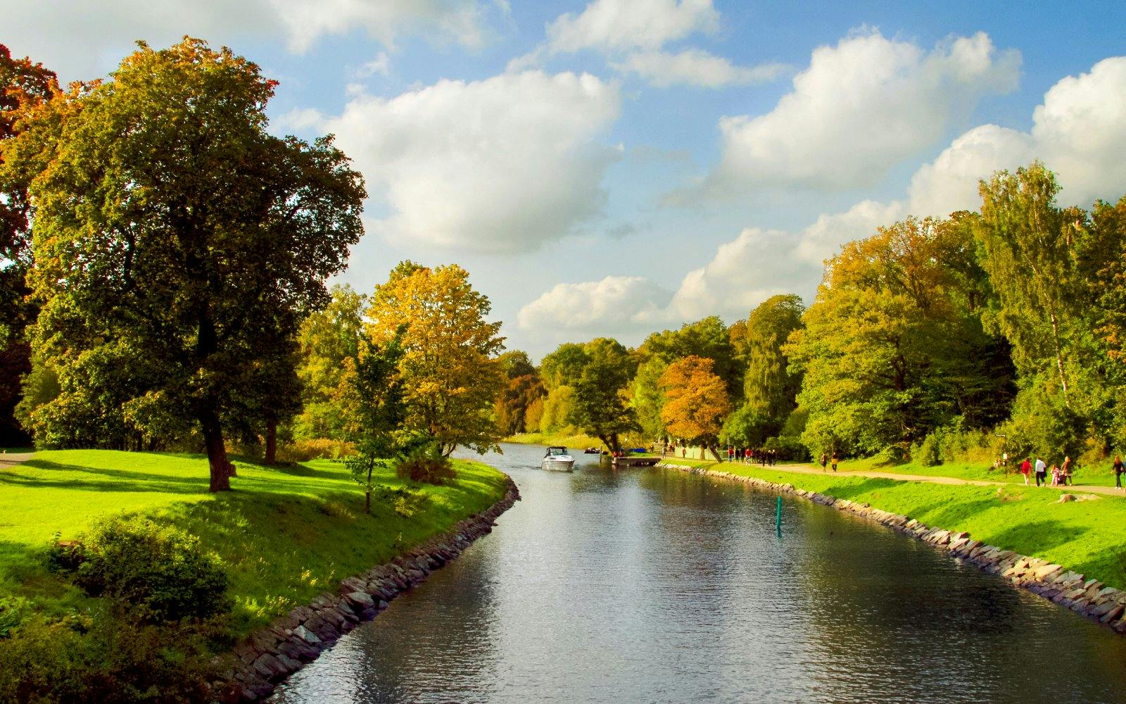 Boat on Djurgårdsbrunn Canal surrounded by autumn trees in Stockholm.