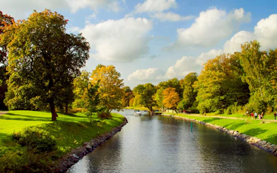 Boat on Djurgårdsbrunn Canal surrounded by autumn trees in Stockholm.