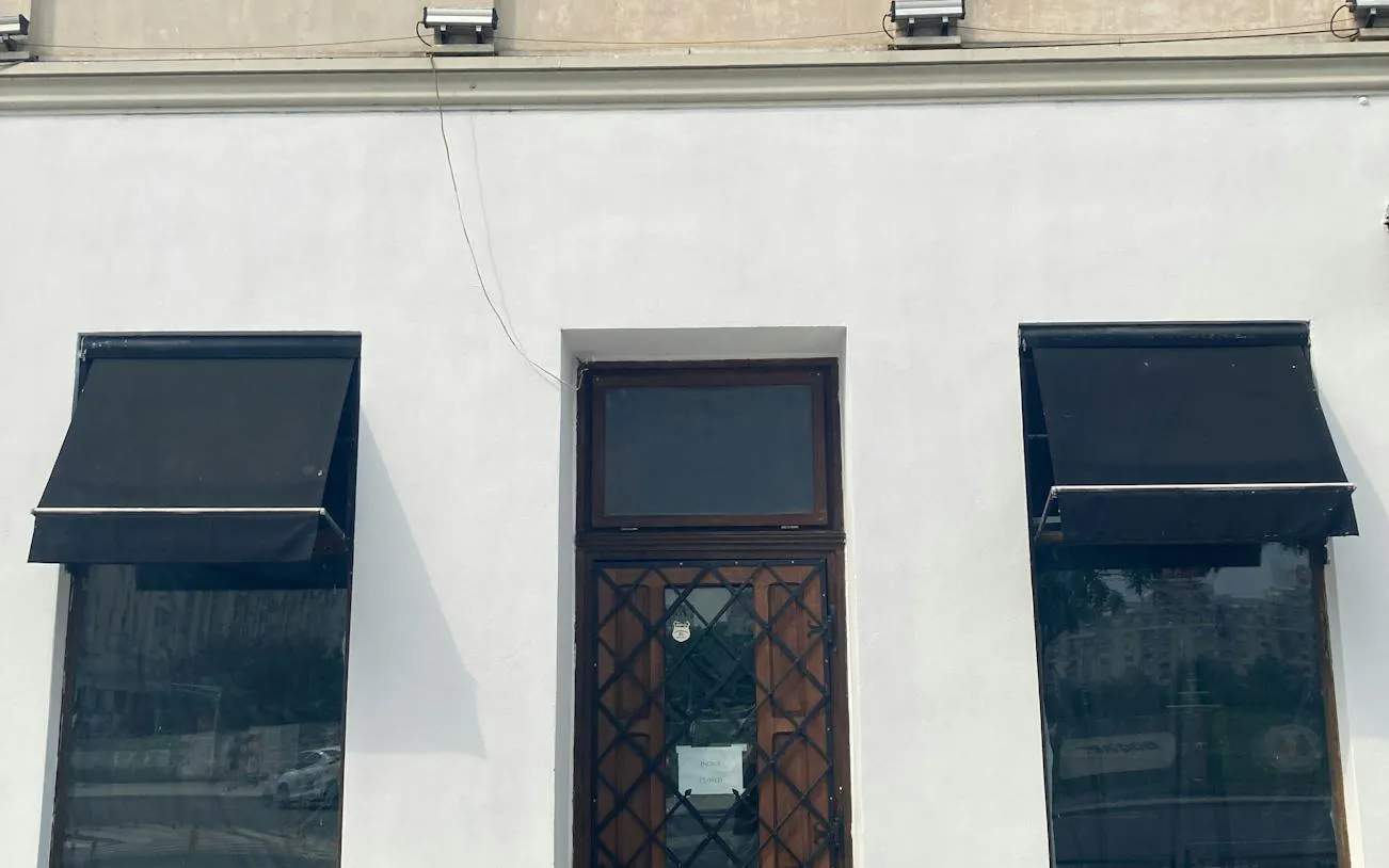 Facade of a building with black awnings and a wooden door in Bucharest, part of the self-guided city exploration game.