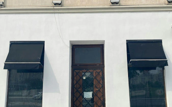 Facade of a building with black awnings and a wooden door in Bucharest, part of the self-guided city exploration game.