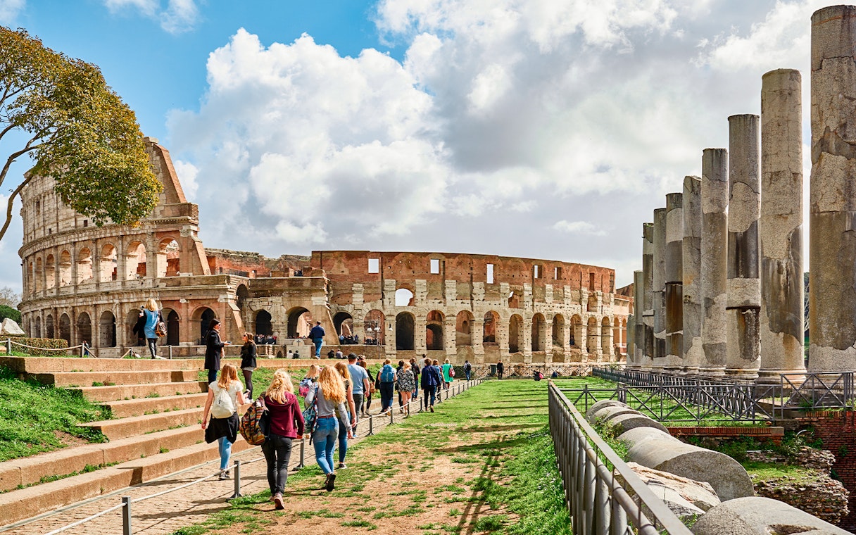 Tourists exploring the Roman Colosseum and nearby ruins in Rome, Italy.