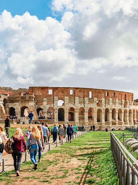 Tourists exploring the Roman Colosseum and nearby ruins in Rome, Italy.