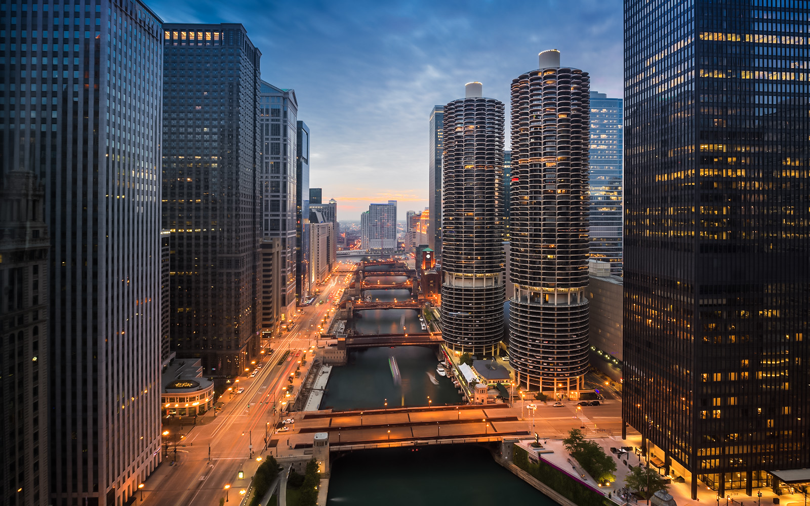 Chicago River at sunset with city skyline and illuminated buildings.