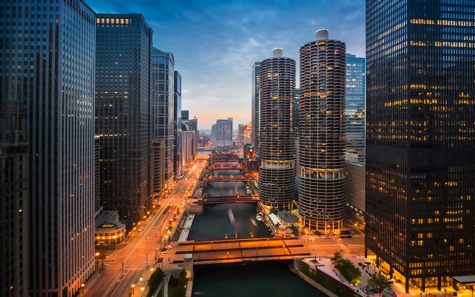 Chicago River at sunset with city skyline and illuminated buildings.