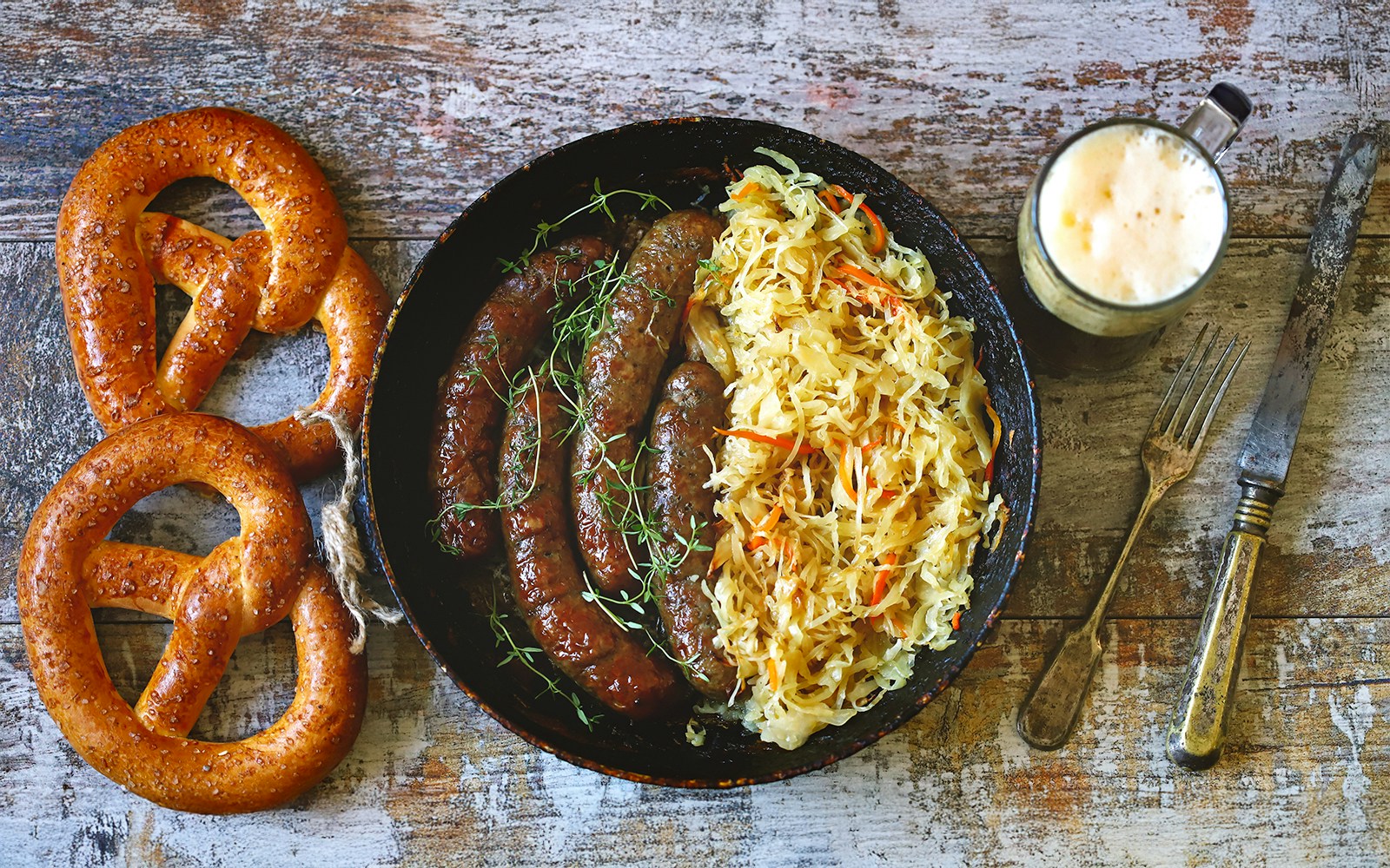 Bratwurst and schnitzel with pretzels and imported beers in a German beer hall setting.