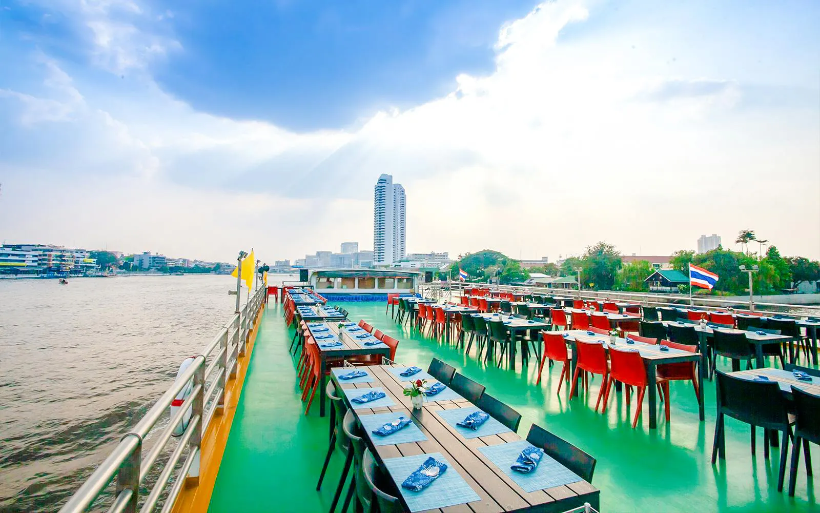 Riverside dining setup on a cruise in Bangkok with city skyline in the background.