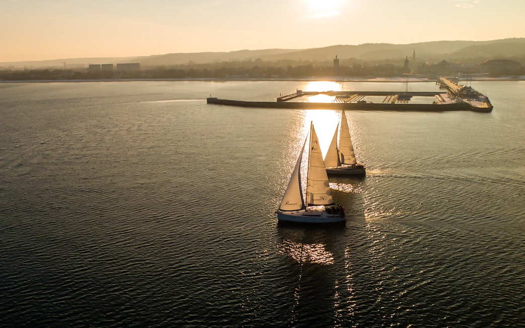 Sailboats on a sunset cruise departing from Sopot Pier.