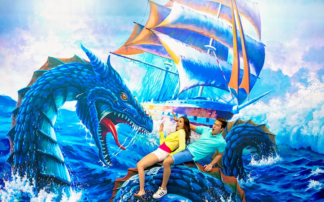Couple interacting with 3D sea monster art at Trick Eye Museum.